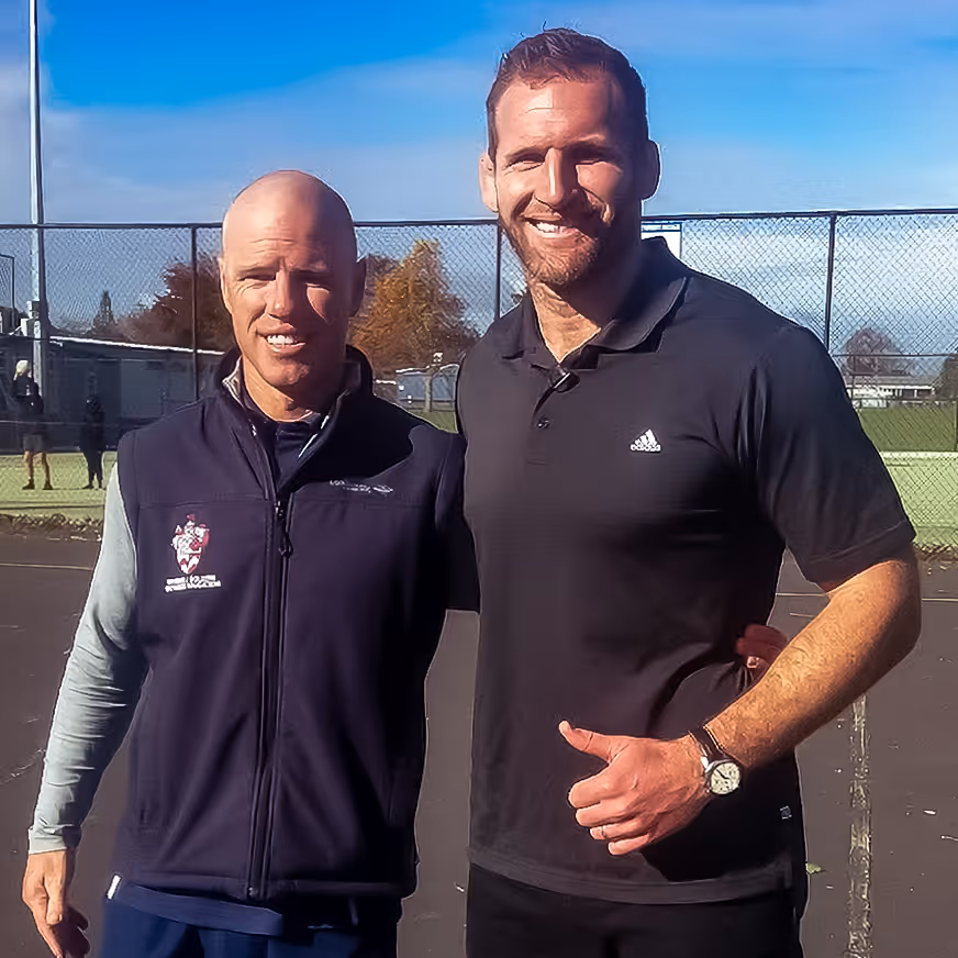 Two visitors smiling together on the tennis courts at Rosehill College